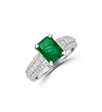 14K white gold ring featuring emerald-cut emerald with three rows of round diamonds on shank

