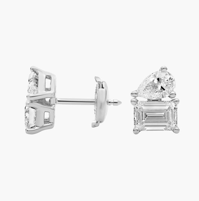 14K white gold emerald and pear cut diamond stud earrings with secure push-back closures on a white background.

